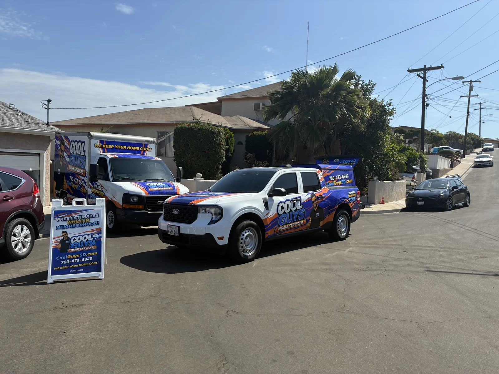 Two wrapped Cool Guys Home Services vehicles parked on a residential street beside a free-estimates sign