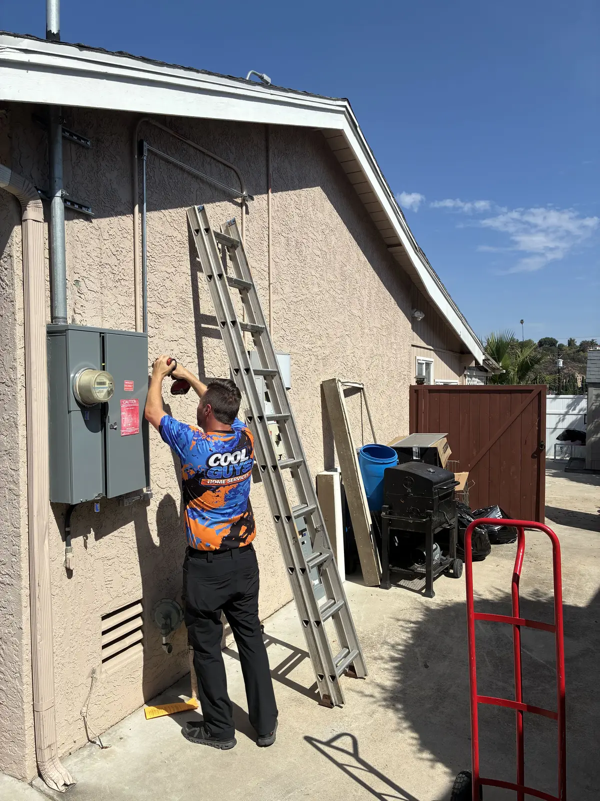 A Cool Guys Home Services technician working at a home's exterior electrical panel and disconnect